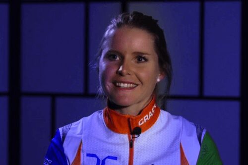 Smiling athlete wearing a white and orange sports jacket.