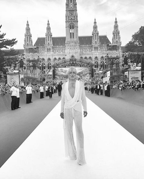 A fashion model walks down a runway with a grand cathedral in the background.