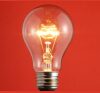 Glowing incandescent light bulb against a red background.
