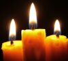 Three glowing candles with bright flames against a dark background.