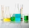 Various laboratory glassware filled with colorful liquids on a white surface.