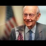 Smiling elderly man with American flag background.