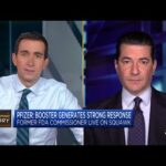 Two men discussing Pfizer booster on TV.