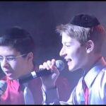 Two boys singing with microphones on stage.