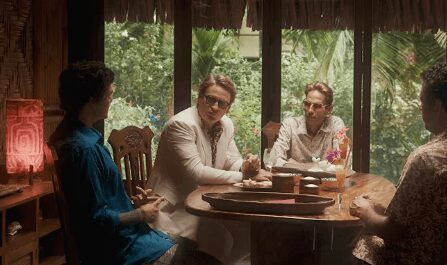 Three men engaged in a serious conversation around a wooden table.