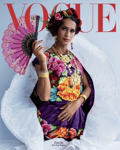 A stylish model poses with a colorful fan and floral dress on a Vogue cover.