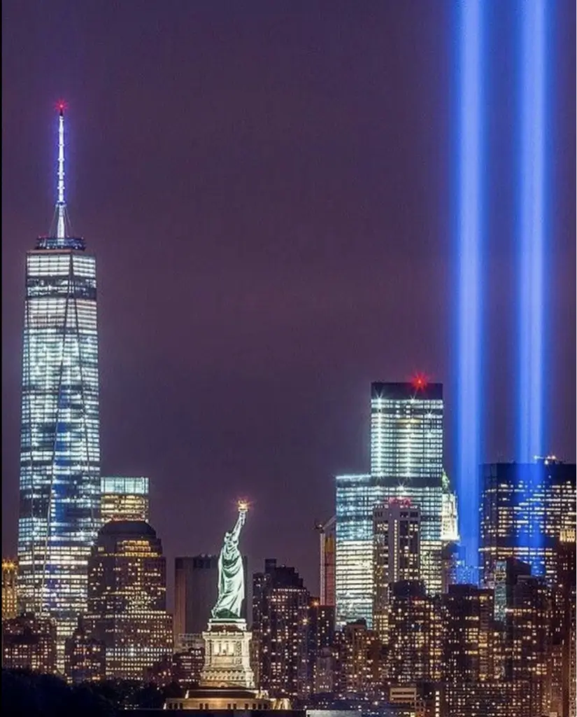 Two vertical beams of light in a city skyline at night.